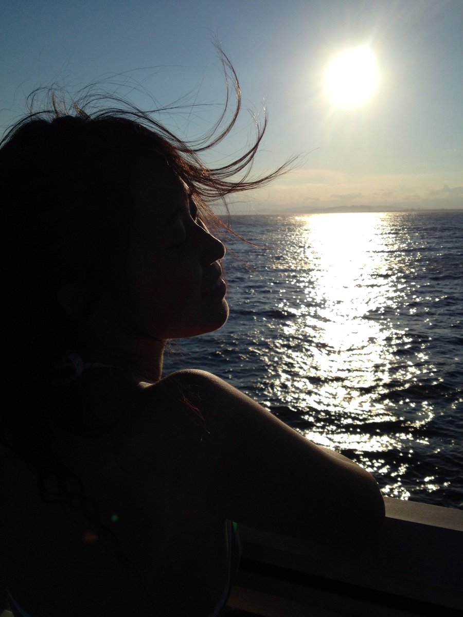 海を背景に、逆光の中で風に髪をなびかせる横顔のシルエット